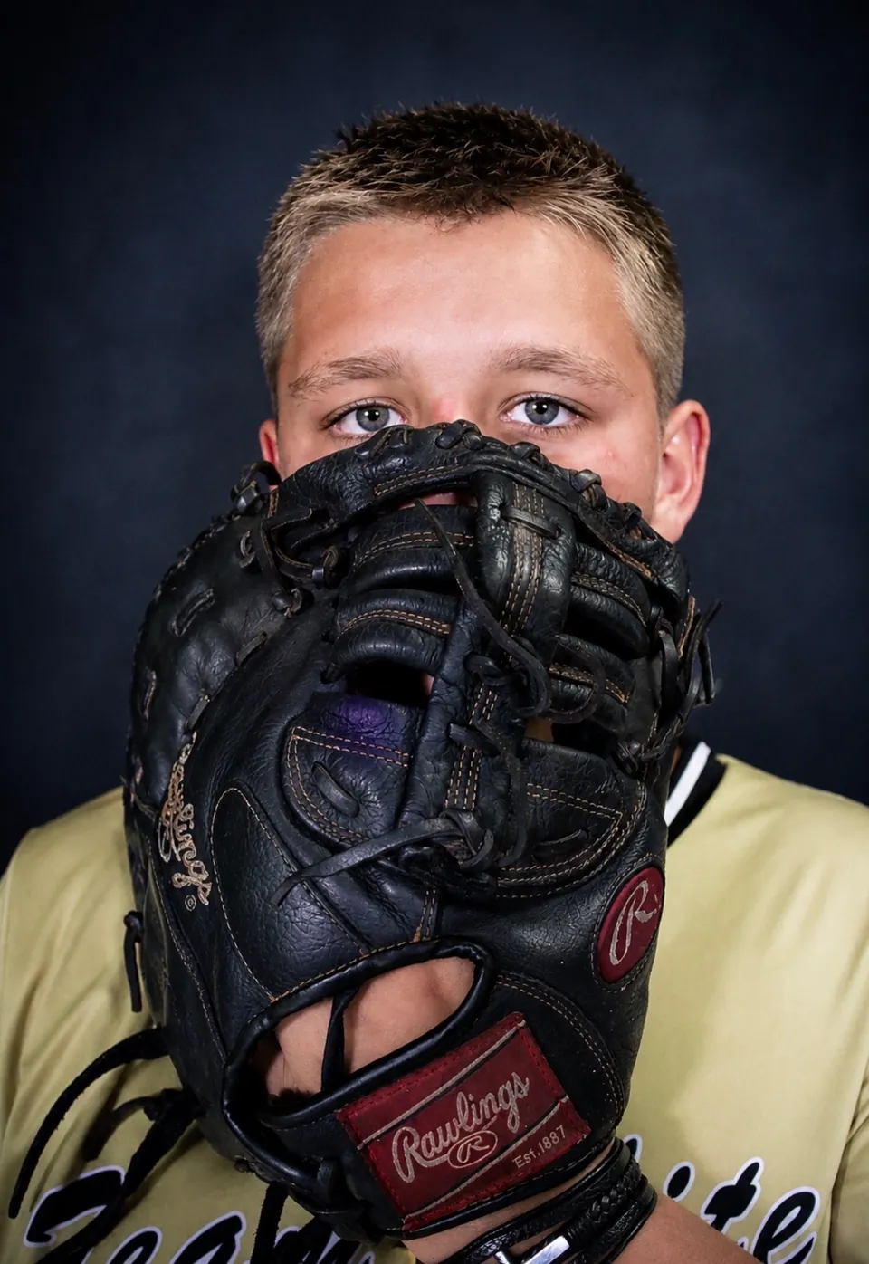 Young baseball player holding his glove over his face