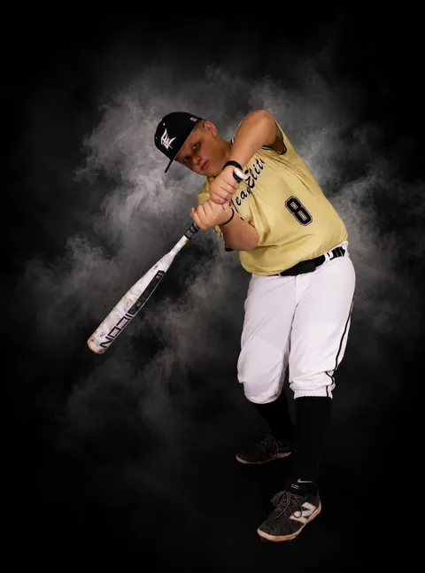 Baseball player mid-swing against a smoky backdrop