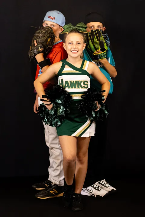 Cheerleader posing in front of two baseball players