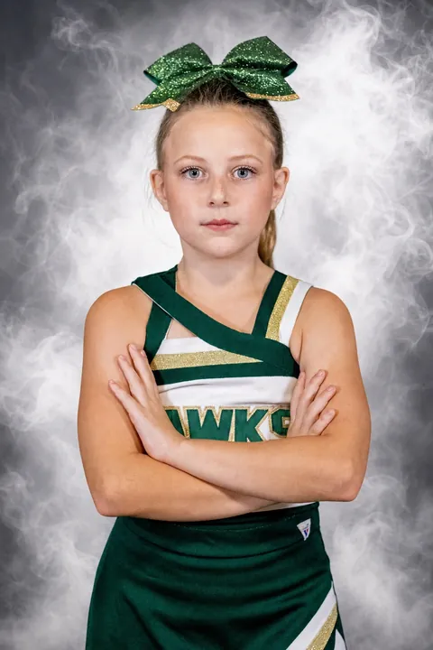 Cheerleader with a green bow posing with arms crossed