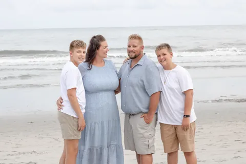 Family of four standing together at the shoreline