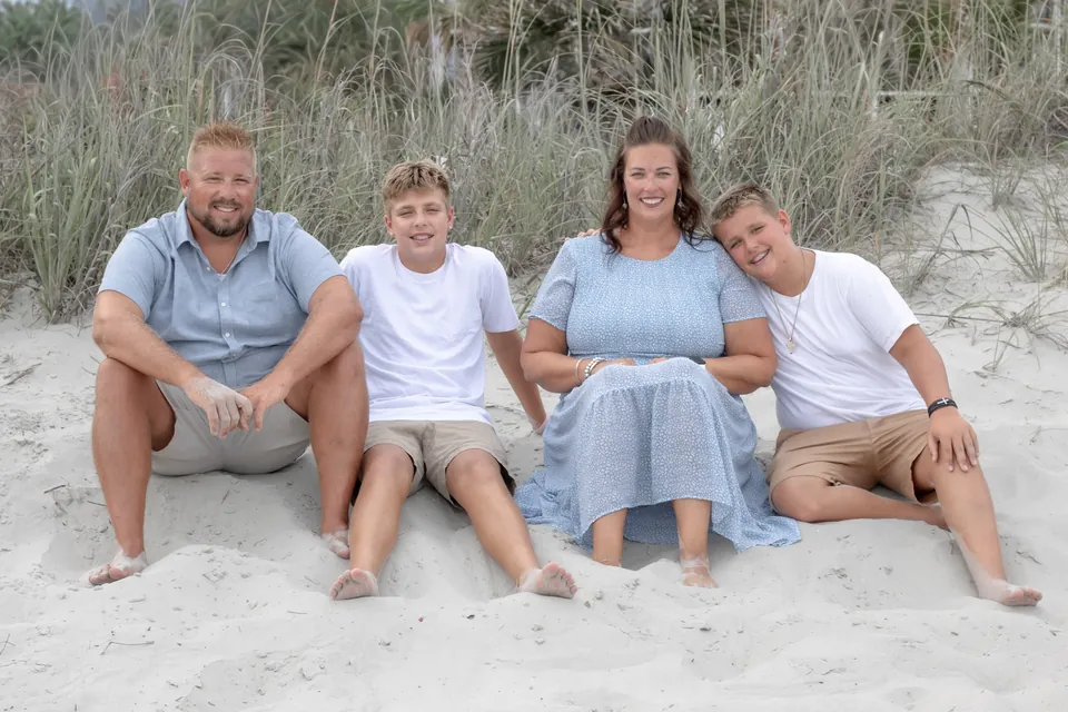 Family of four sitting together on the beach dunes