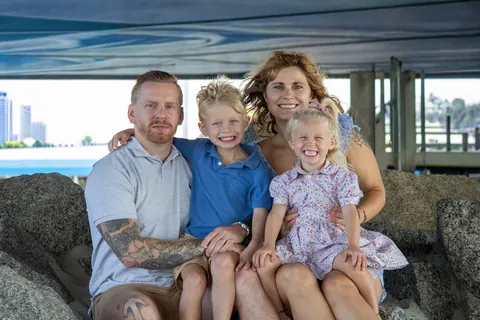 Family of four sitting on the rocks under a pier