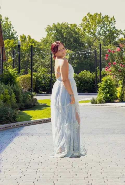 Woman in a flowing blue gown in a garden courtyard