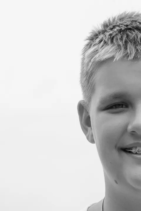 Black and white half-face portrait of a smiling boy