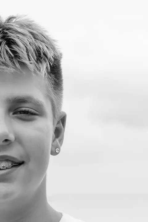 Black and white half-face portrait of a smiling boy
