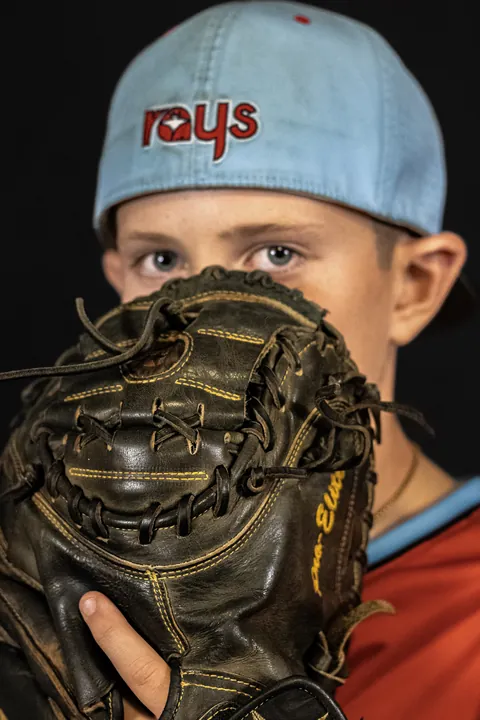 Young player peering over his baseball glove