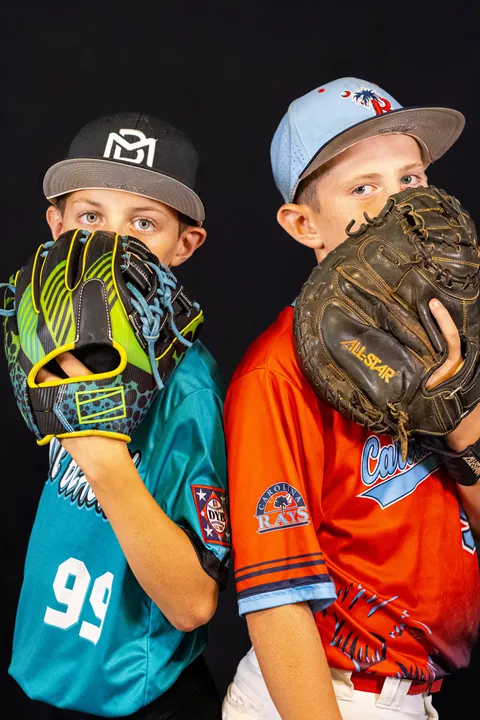 Two young players posing behind their baseball gloves